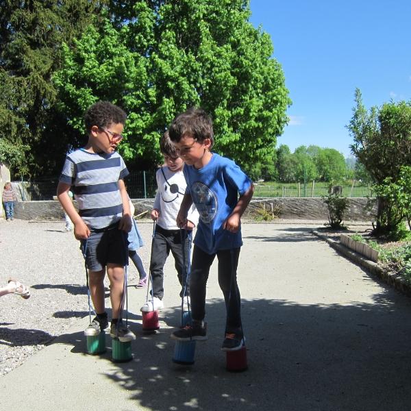 Les enfants jouent aux échasses dans la cour